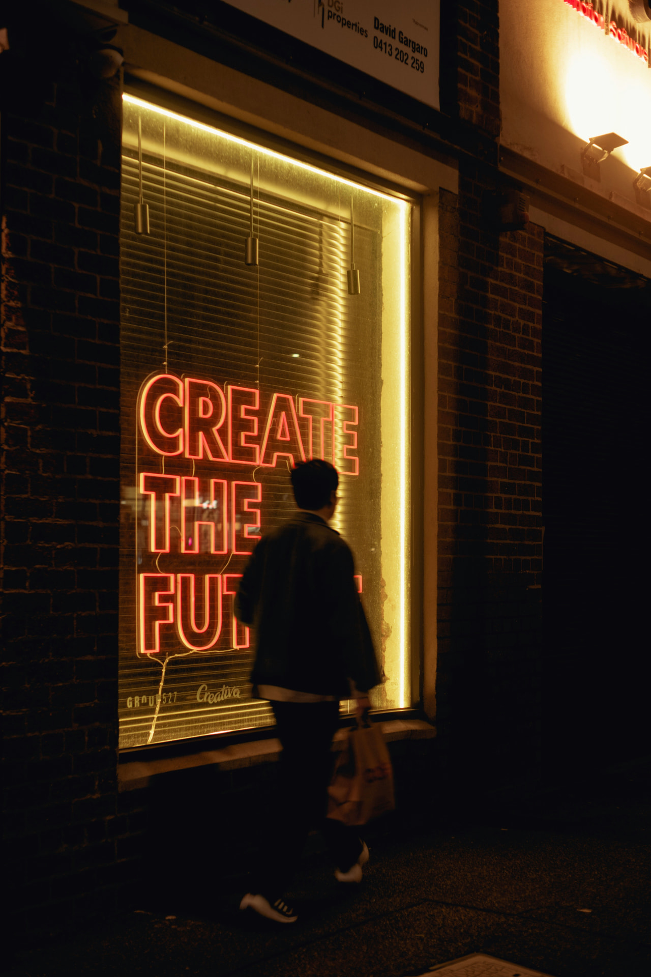 Neon CREATE THE FUTURE sign glowing in a dark street at night