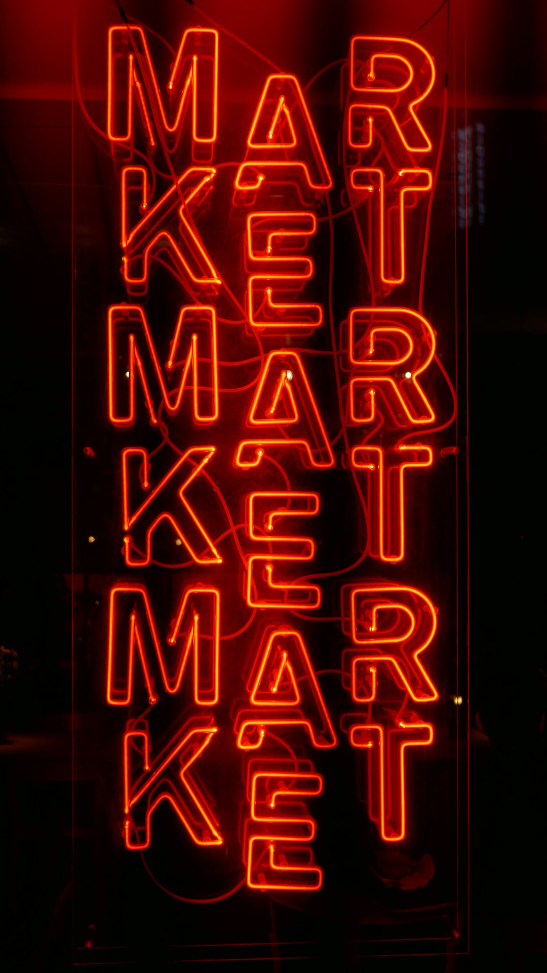 Red neon sign spelling MARKET repeated on a dark background